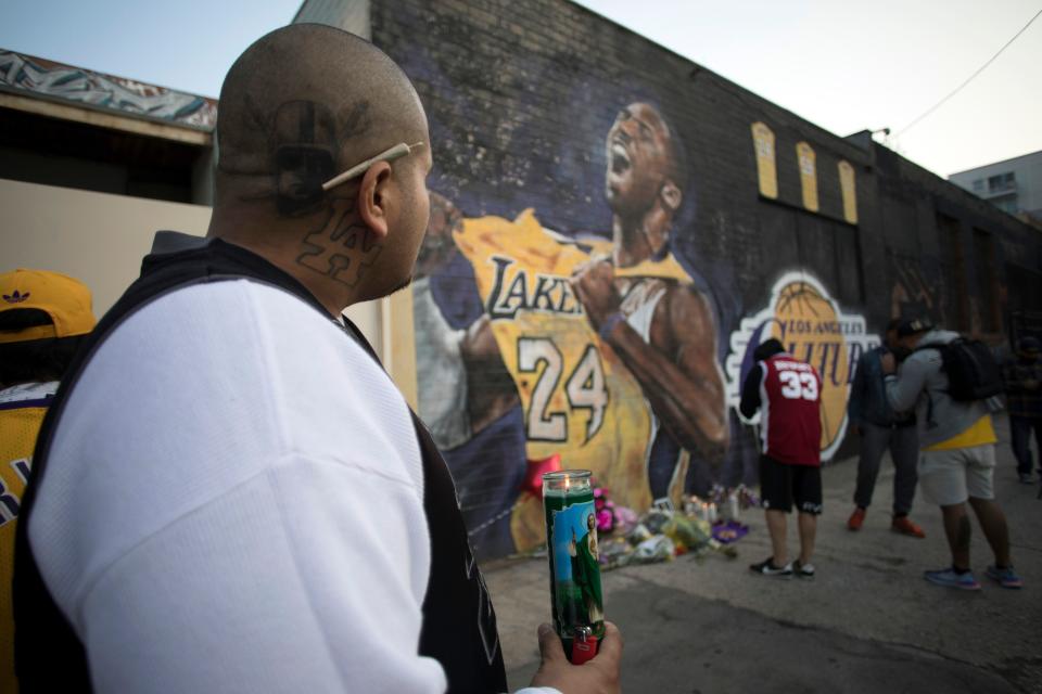 Luis Villanueva lights a candle in front of a Kobe Bryant mural in downtown Los Angeles on January 26, 2020. - Nine people were killed in the helicopter crash which claimed the life of NBA star Kobe Bryant and his 13 year old daughter, Los Angeles officials confirmed on Sunday. Los Angeles County Sheriff Alex Villanueva said eight passengers and the pilot of the aircraft died in the accident. The helicopter crashed in foggy weather in the Los Angeles suburb of Calabasas. Authorities said firefighters received a call shortly at 9:47 am about the crash, which caused a brush fire on a hillside. (Photo by Apu GOMES / AFP) (Photo by APU GOMES/AFP via Getty Images)