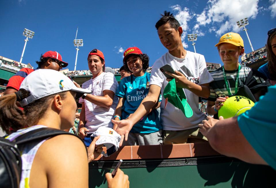 Iga Swiatek of Poland signs autographs for fans after winning the WTA singles title at the BNP Paribas Open at the Indian Wells Tennis Garden in Indian Wells, Calif., Sunday, March 20, 2022. 