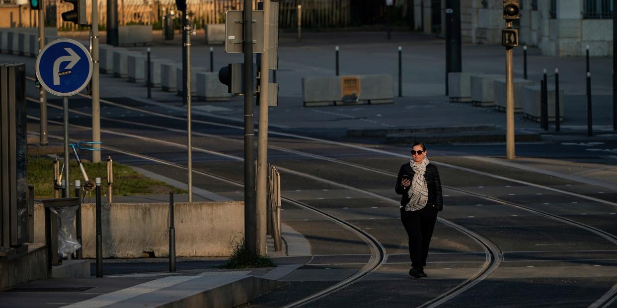 A woman walks on empty tram rails in Lyon, central France, Monday, March 23, 2020. French citizens are only allowed to leave their homes for necessary activities such as shopping for food, going to work or taking a quick walk due to the rapid spreading of the new coronavirus in the country. For most people, the new coronavirus causes only mild or moderate symptoms. For some it can cause more severe illness, especially in older adults and people with existing health problems. (AP Photo/Laurent Cipriani)