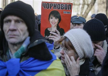 A protester holds a picture of journalist Tetyana Chornovil, who was beaten and left in a ditch just hours after publishing an article on the assets of top government officials, during a protest rally in front of the Ukrainian Ministry of Internal Affairs in Kiev December 26, 2013. REUTERS/Gleb Garanich