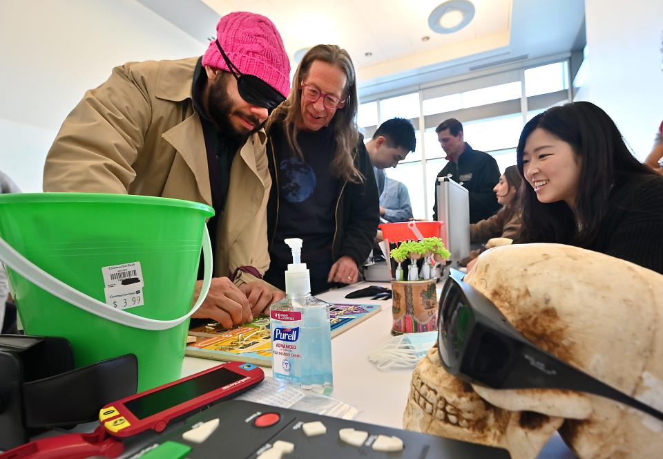 Blind-folded Jorge Fuentes of Worcester tries to unlock a series of locks in an adaptive puzzle as guide Michael Milligan of Worcester, center, and medical student Euna Lee of Chestnut Hill look on. They are at a booth that promoted eyecare.