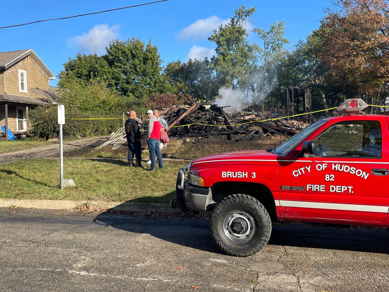 A pair of Hudson firefighters speak with a homeowner whose house burned down in the twilight hours of Monday, Oct. 9.