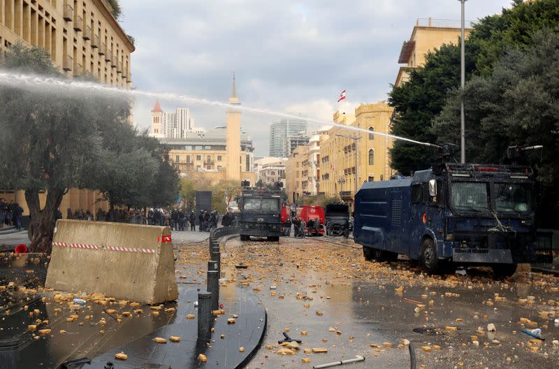 A police vehicle sprays with water cannon during a protest seeking to prevent MPs and government officials from reaching the parliament for a vote of confidence, in Beirut