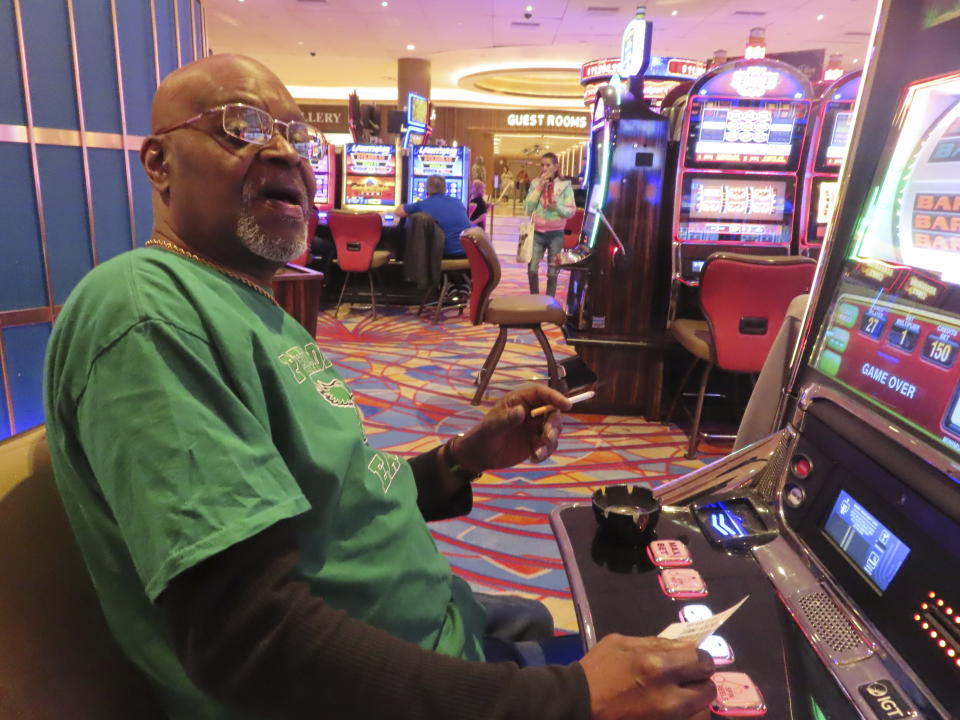 Steve Mitchell, of Wilmington, Del., smokes while he plays a slot machine at the Hard Rock casino in Atlantic City, N.J., on Feb. 2, 2024. Competing bills in the New Jersey Legislature in February 2024 would either ban smoking outright in Atlantic City's nine casinos or allow it to continue with additional restrictions. (AP Photo/Wayne Parry)