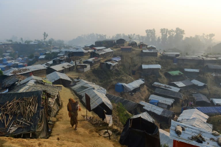 Photo taken last November shows a Rohingya refugee woman walking with a child in her lap in Balukhali refugee camp in Bangladesh