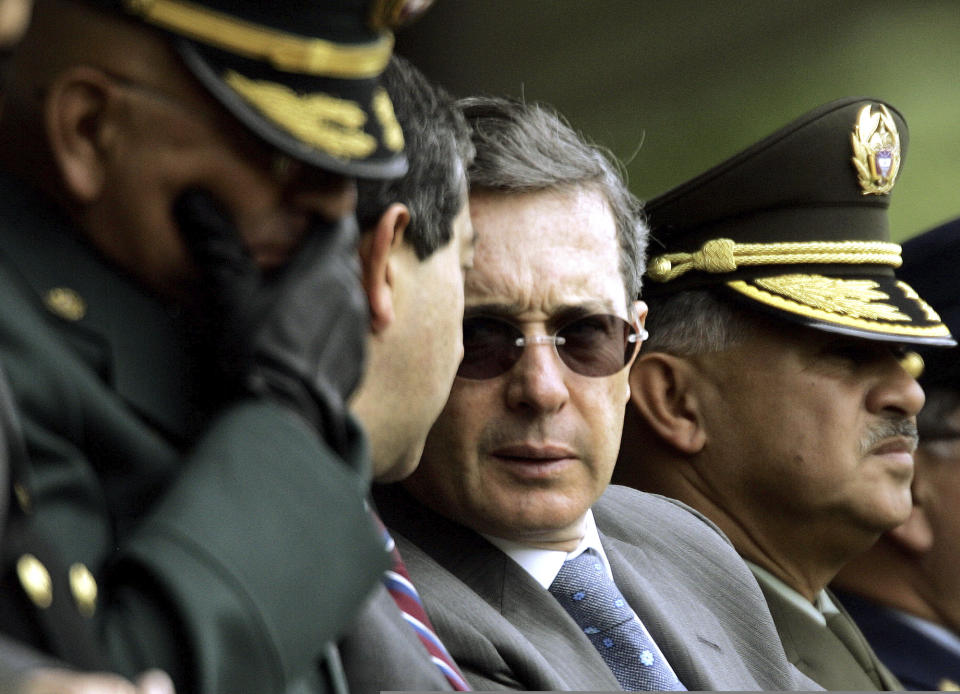 FILE - In this June 9, 2006 file photo, Colombia's President Alvaro Uribe, center, speaks with Defense Minister Camilo Ospina, second left, during a police ceremony in Bogota, Colombia. The U.S. Department of Defense suspected back then that the now former president harbored ties with violent paramilitaries but likened it to a necessary evil in the fight against leftist rebels, according to a newly declassified memo from his early years in office. (AP Photo/Fernando Vergara, File)