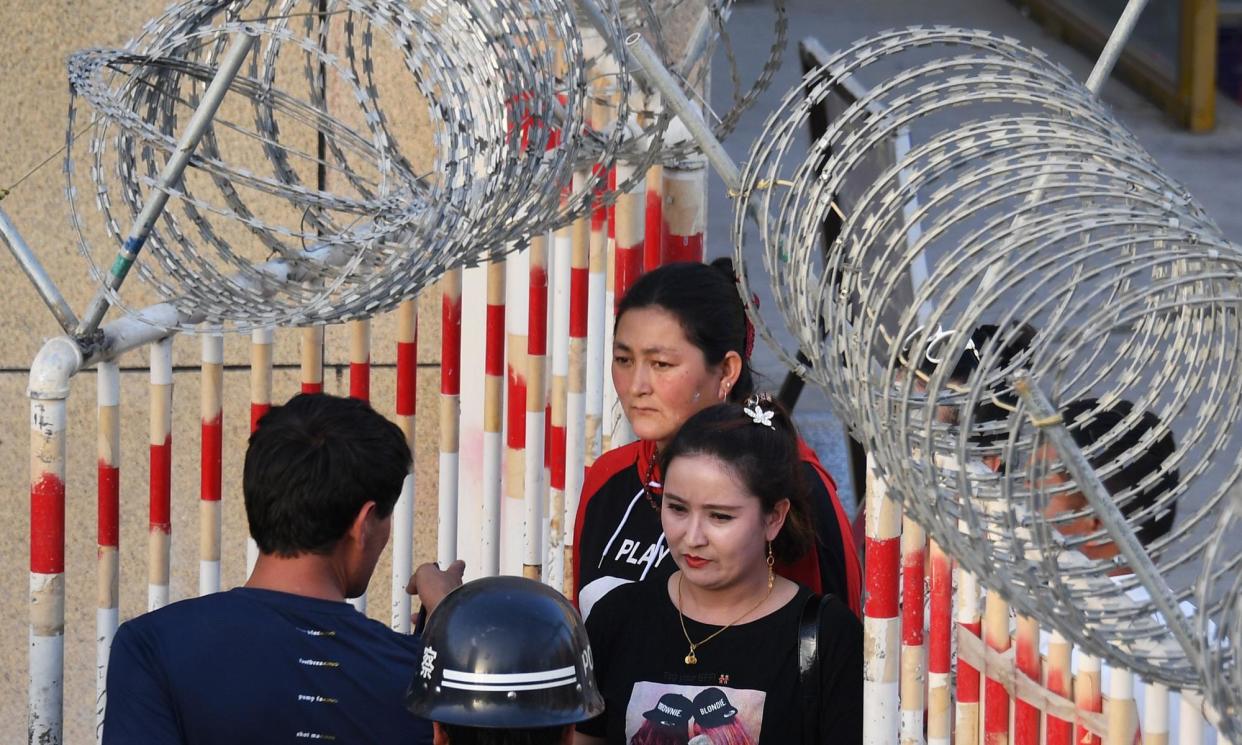 <span>Two women pass through a secure entrance to a bazaar in Xinjiang in 2019. Life for Uyghur Muslims in the region is strictly controlled, with increasing surveillance and militarisation.</span><span>Photograph: Greg Baker/AFP/Getty Images</span>