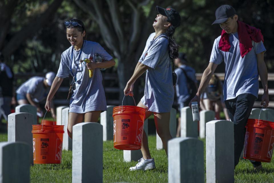 Mikaela Garcia, 20, left, Eunice Kim and Justin Lee carry heavy buckets.