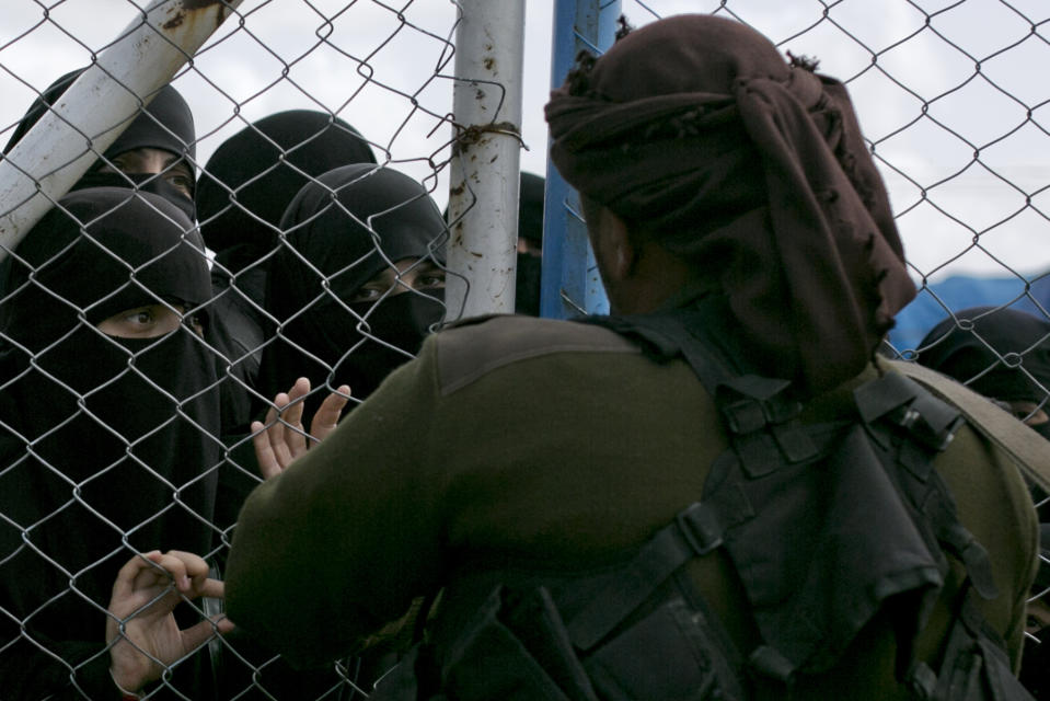 In this March 31, 2019, photo, women speak to guards at the gate that closes off the section for foreign families who lived in the Islamic State's so-called caliphate, at al-Hol camp in Hasakeh province, Syria. As Turkish troops invade northern Syria and the U.S. abandons its Kurdish allies, there are renewed fears of a prison break in the camp that could give new life to the extremist group. (AP Photo/Maya Alleruzzo)