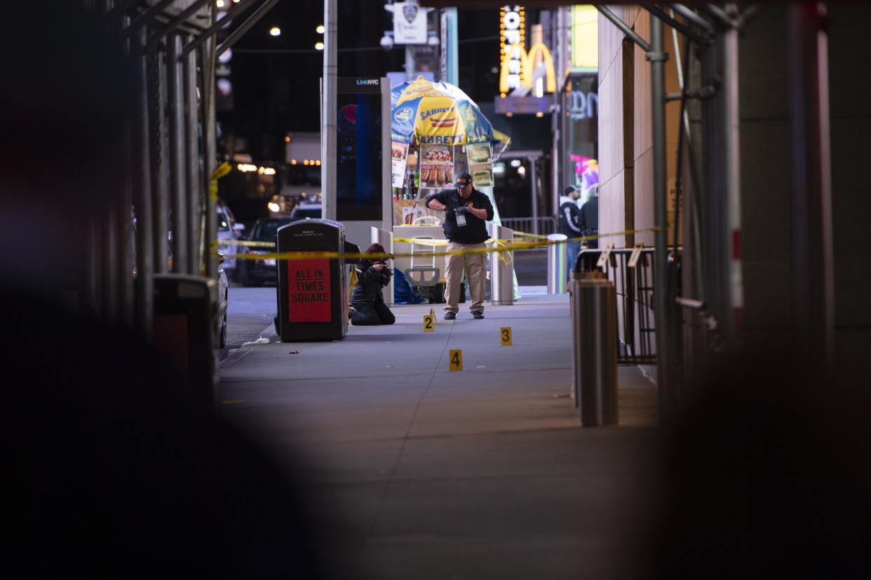 Police recover shell casings on the sidewalk of 45th Street near 7th Avenue in Manhattan, after a shooting in Times Square on Saturday.