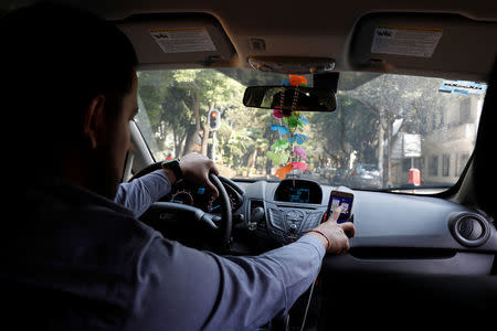 An Uber driver checks the route on a mobile phone inside his car in Mexico City, Mexico February 6, 2018. Picture taken on February 6, 2018. REUTERS/Carlos Jasso