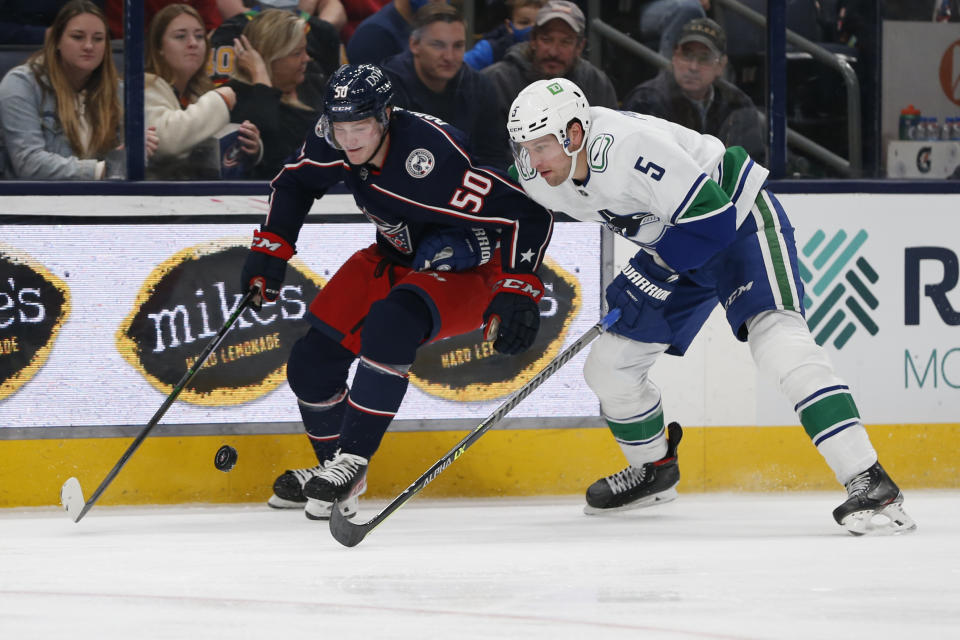 Columbus Blue Jackets' Eric Robinson, left, and Vancouver Canucks' Tucker Poolmann chase a loose puck during the second period of an NHL hockey game Friday, Nov. 26, 2021, in Columbus, Ohio. (AP Photo/Jay LaPrete)