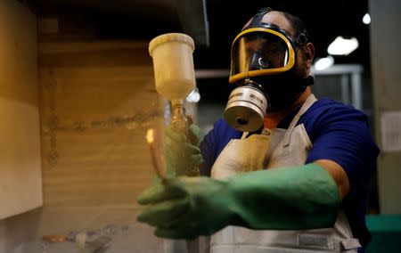 A worker from the Casa da Moeda do Brasil (Brazilian Mint) varnishes a Rio 2016 Olympic medal in Rio de Janeiro, Brazil, June 28, 2016. REUTERS/Sergio Moraes