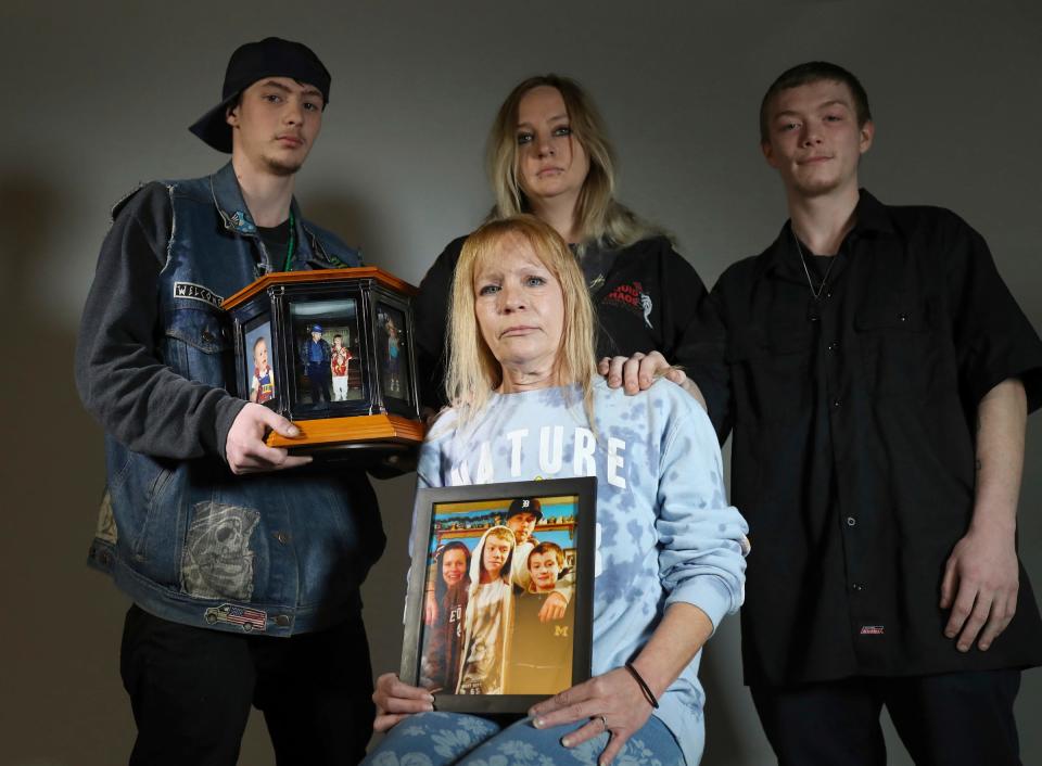 Cynthia Cooper, mother of Shane Cousins, holds a family photo as she poses with, Stone Cousins, 23,  Jessica Cooper, 34, and Shannon Cousins, 26, on Monday, April 3, 2023. Shane was shot and killed by Michigan State Police officers after he shot at a police helicopter.