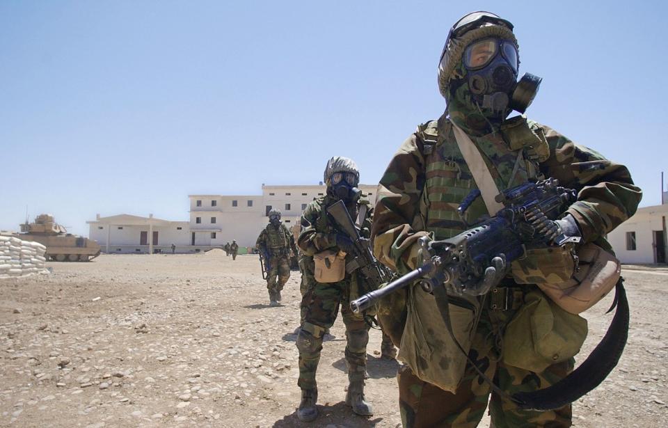 US Army soldiers wearing full chemical protection suits walk inside the courtyard of an industrial complex they secured which they thought was a possible site for weapons of mass destruction in the central Iraqi town of Baquba in May 2003. The building, which was used as a bread factory, was secured without any incidents and no WMD were found.