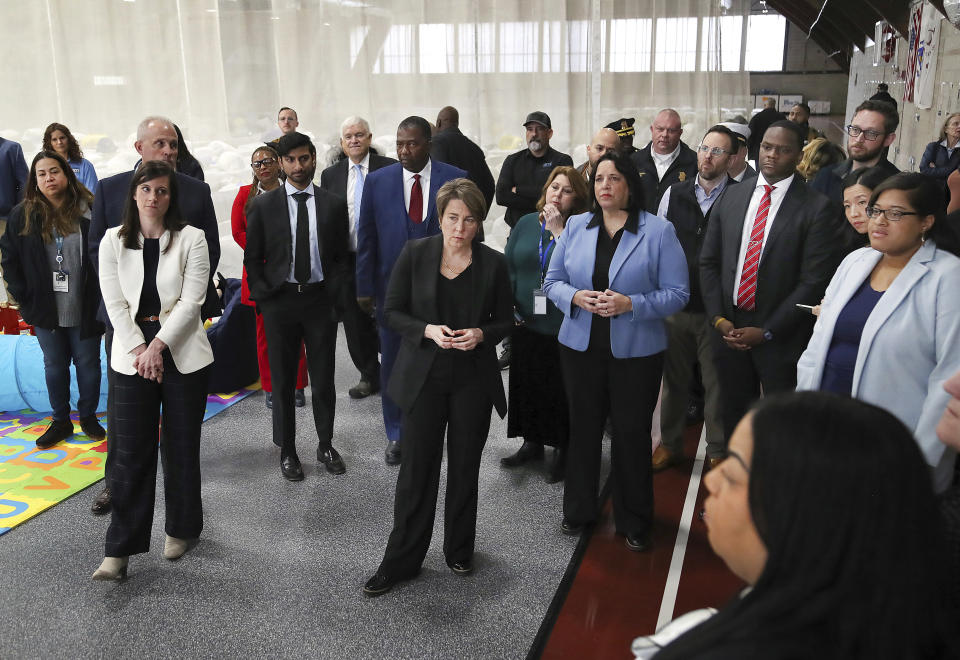 State and local officials toured the Melnea A. Cass Recreational Complex on Wednesday, Jan. 31, 2024, including Governor Maura Healey, center, and Lt. Gov Kim Driscoll, center right, in the Roxbury neighborhood of Boston. They listen to remarks about the planned use of the facility to house over 300 migrants. (John Tlumacki/The Boston Globe via AP, Pool)