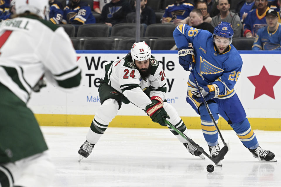 St. Louis Blues' Nathan Walker (26) competes for the puck against Minnesota Wild's Zach Bogosian (24) during second period of an NHL hockey game Saturday, March 2, 2024, in St. Louis. (AP Photo/Michael Thomas)