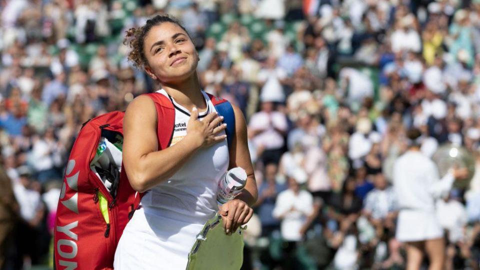 Jasmine Paolini sonríe mientras lleva su bolsa de tenis
