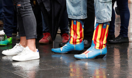 A voter wearing a pair of boots decorated with the Estelada (Catalan separatist flag) waits outside a polling station during the banned independence referendum in Barcelona Spain, October 1, 2017. REUTERS/Yves Herman