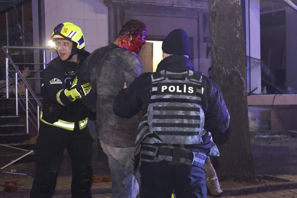In this photo provided by the Ukrainian Emergency Service, police and emergency workers help a wounded resident after an apartment building where he lived was hit by a Russian missile in Kharkiv, Ukraine, Saturday, Dec. 30, 2023. (Ukrainian Emergency Service via AP)