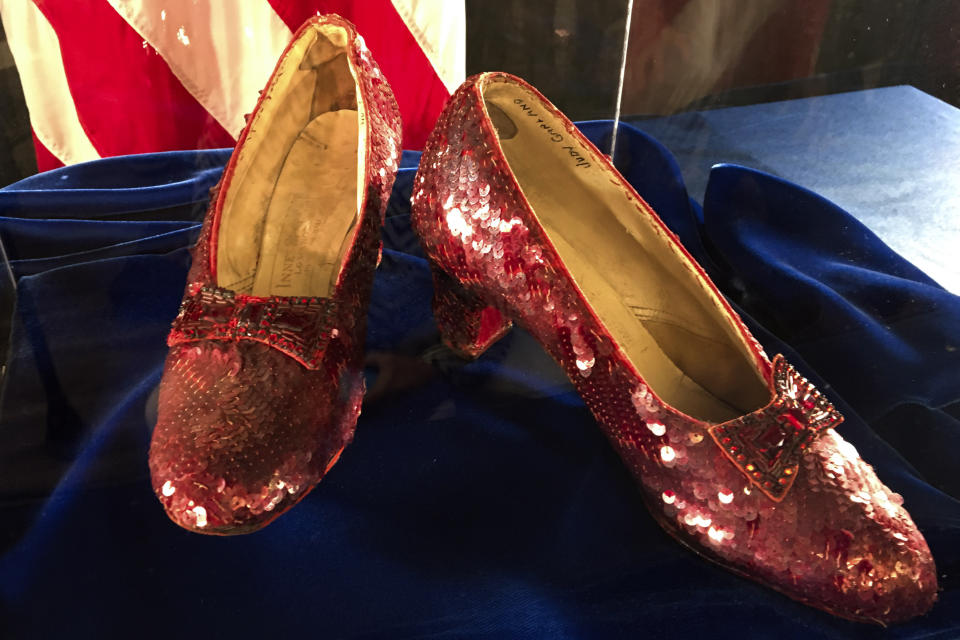 ARCHIVO - Las zapatillas de rubí que alguna vez usó Judy Garland en "El mago de Oz" se exhiben en una conferencia de prensa, el 4 de septiembre de 2018, en la oficina del FBI en Brooklyn Center, Minnesota. En una extraña peculiaridad de los derechos de "El mago de Oz", las zapatillas de rubí de Dorothy, siguen siendo propiedad intelectual de MGM por la película de 1939. En la novela original de Frank Baum, publicada en 1900, los zapatos son plateados. (Foto AP/Jeff Baenen, archivo)