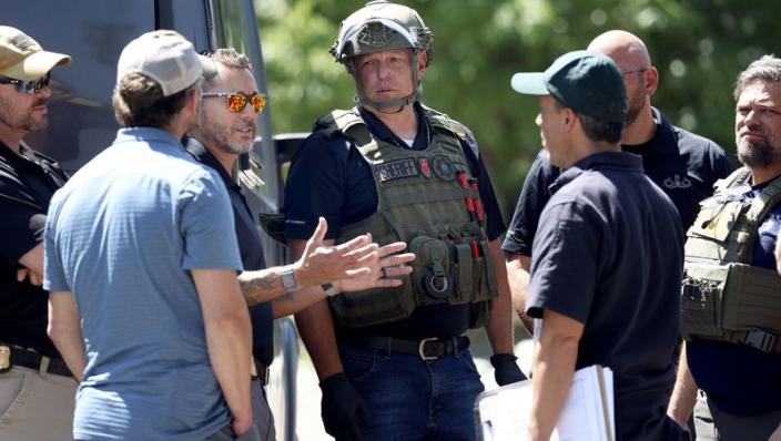 Law enforcement agents confer at the home of Craig Deeleuw Robertson who was shot and killed by FBI agents in Provo on Wednesday, Aug. 9, 2023. Robertson allegedly posted threatening comments about President Joe Biden hours before the president was scheduled to visit Utah.