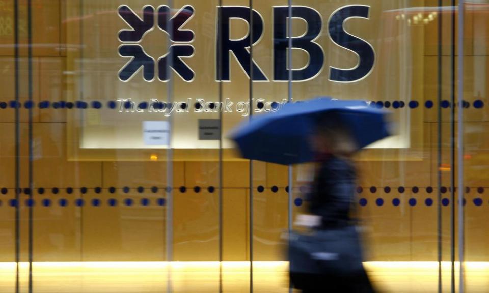 a woman with a brolley passes an RBS branch