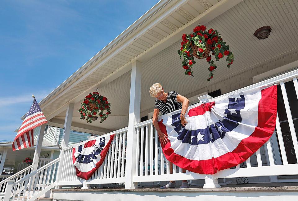 Hull resident Dottie MacDonald, of Warren Street, puts bunting on her porch to prepare for the July Fourth weekend on Monday, June 28, 2021.