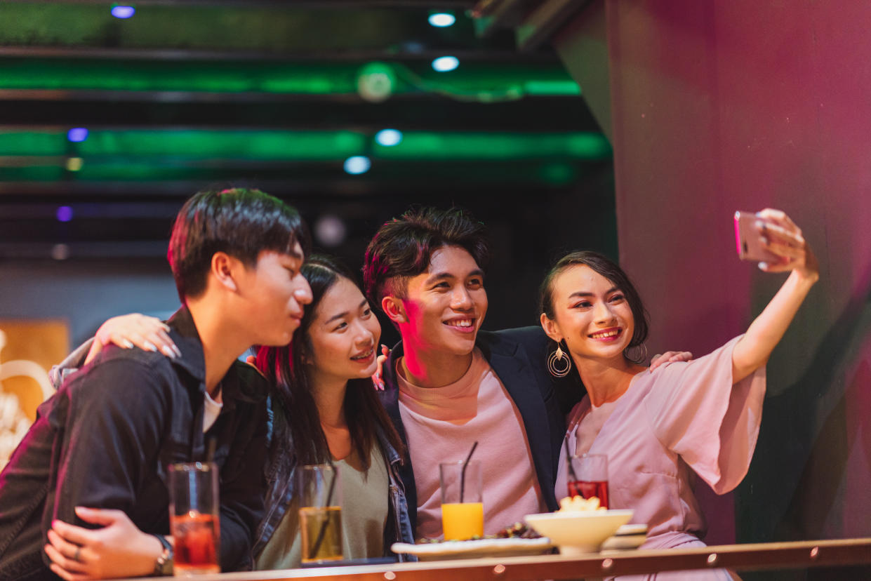 Four young friends take a selfie in a pub.