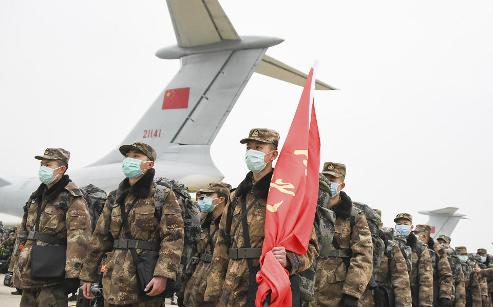 In this photo released by China's Xinhua News Agency, Chinese military medical staff members stand in formation after arriving at Wuhan Tianhe International Airport in Wuhan in central China's Hubei Province, Sunday, Feb. 2, 2020. The Philippines on Sunday reported the first death from a new virus outside of China, where authorities delayed the opening of schools in the worst-hit province and tightened quarantine measures in a city that allow only one family member to venture out to buy supplies. (Cheng Min/Xinhua via AP)