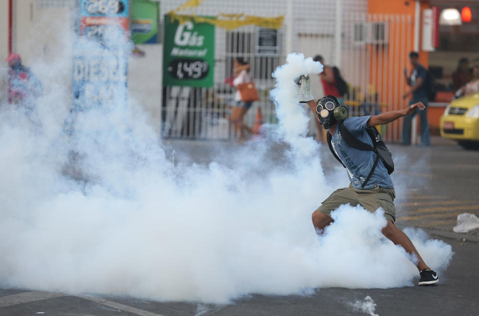A demonstrator winds up to return a tear gas grenade to police, outside the central train station, during a protest against the increase on bus fares in Rio de Janeiro, Brazil, Thursday, Feb. 6, 2014. It's the latest protest to hit Brazil since last June. The anti-government demonstrators are angered by poor public services in return for their high tax rate. Fueling anger has been the billions spent to host this year's World Cup. (AP Photo/Leo Correa)