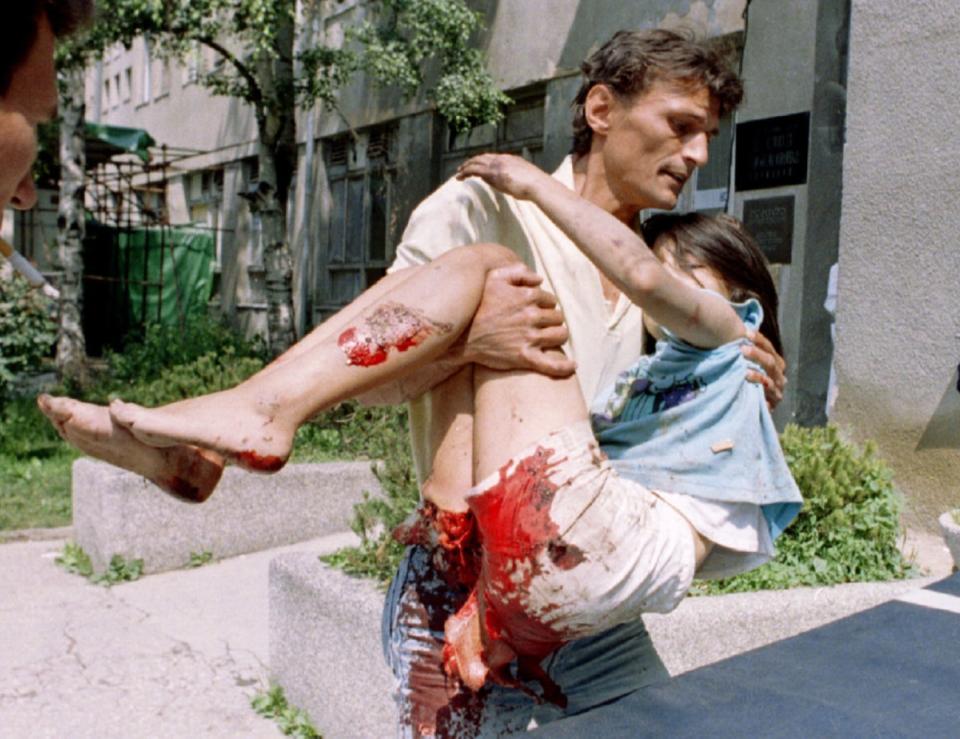 <p>Un trabajador humanitario lleva a una niña de 11 años gravemente herida por un proyectil al hospital de Kosevo, en julio de 1995. (Foto: Reuters). </p>