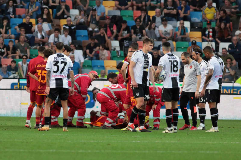 Rome's Evan Ndicka (C) is prepared for evacuation by paramedics after a medical emergency during the Italian serie A soccer match between Udinese Calcio and AS Rom at Bluenergy Stadium. Andrea Bressanutti/LaPresse via ZUMA Press/dpa