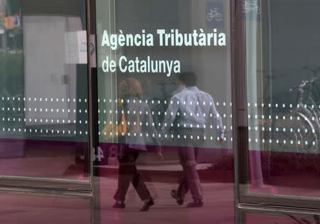 A couple is reflected on a glass of the Catalan Tax Agency in Barcelona, Spain, September 18, 2017. REUTERS/Albert Gea