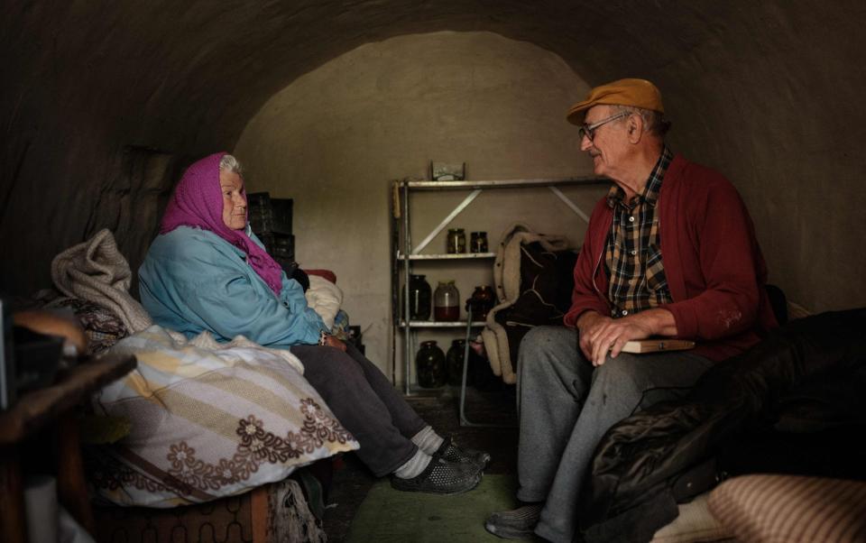 Ukrainian biology professor Oleksiy Polyakov, 84, and his wife Galina, 81, chat as they sit in their vegetable cellar transformed into a shelter in Sydorove, eastern Ukraine - YASUYOSHI CHIBA/AFP