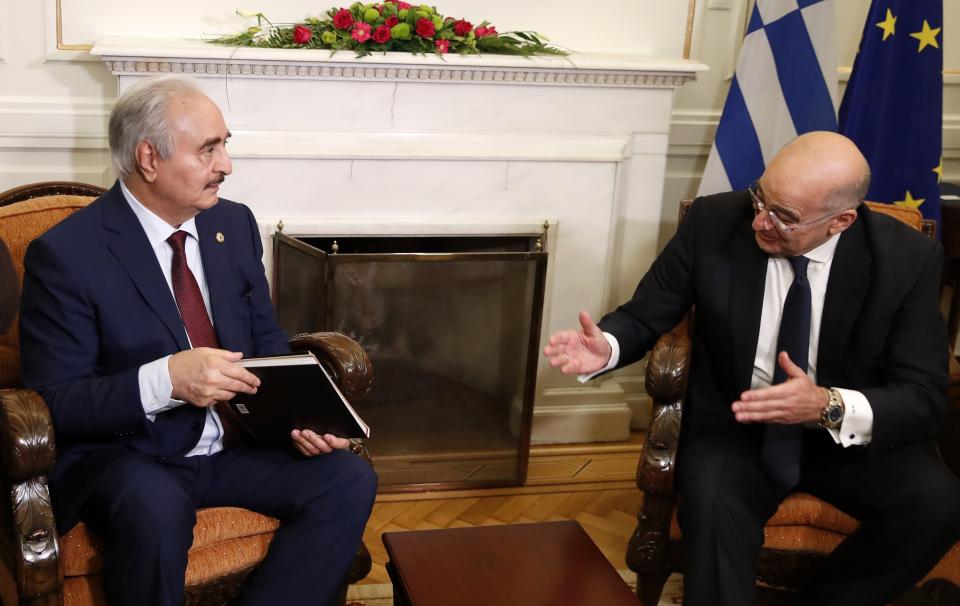 Libyan Gen. Khalifa Hifter, left, receives a book as a gift from the Greek Foreign Minister Nikos Dendias during their meeting in Athens, Friday, Jan. 17, 2020. The commander of anti-government forces in war-torn Libya has begun meetings in Athens in a bid to counter Turkey's support for his opponents. (AP Photo/Thanassis Stavrakis)