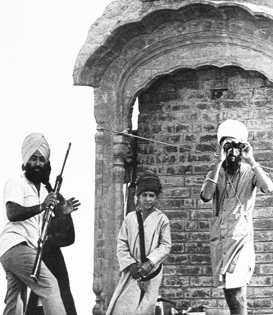 FILE - A Sikh militant holds field glasses to look at government troops from his perch on the Golden Temple in Amritsar as the Indian Army moved men into positions near the temple complex, June 5, 1984. On June 6, 1984, Indian troops attacked to flush out occupying militants. About 1,200 people died in the fighting. The storming of the temple followed weeks of growing tension between the government of Prime Minister Indira Gandhi and Sikhs in the northern state of Punjab. Gandhi was killed in reprisal by her Sikh bodyguards four months later. (AP Photo/Sondeep Shankar, File)