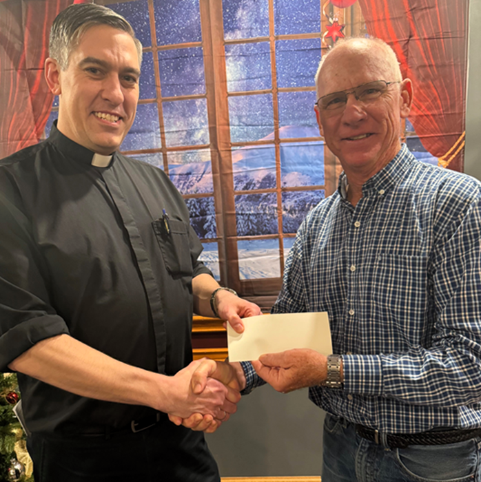 The Rev. Dave Young of St. Nicholas and St. Thomas Aquinas Catholic churches receives $1,000 for each church from Grand Knight Hugh Maxwell of the Knights of Columbus Council 505.