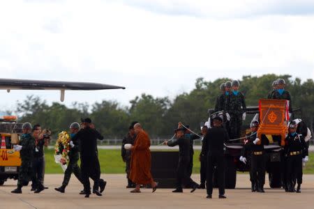 A buddhist monk leads an honour guard carrying the coffin of Samarn Poonan, 38, a former member of Thailand's elite navy SEAL unit who died working to save 12 boys and their soccer coach trapped inside a flooded cave, at Chiang Rai airport, Thailand, July 6, 2018. REUTERS/Stinger