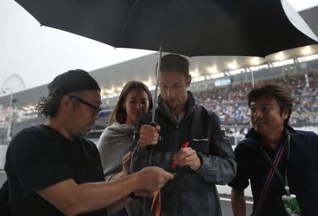 McLaren Formula One driver Jenson Button of Britain, with Jessica Michibata, signs autographs for fans at the Suzuka circuit in Suzuka, western Japan, October 2, 2014, ahead of Sunday's Japanese F1 Grand Prix. REUTERS/Yuya Shino