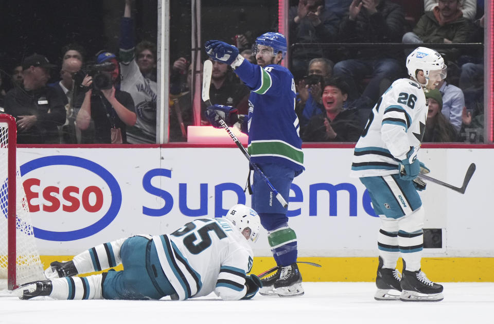 Vancouver Canucks' Conor Garland, back centre, celebrates his goal as San Jose Sharks' Derrick Pouliot, bottom left, lies on the ice and Andrew Agozzino (26) skates past during the second period of an NHL hockey game in Vancouver, British Columbia, Thursday, March 23, 2023. (Darryl Dyck/The Canadian Press via AP)