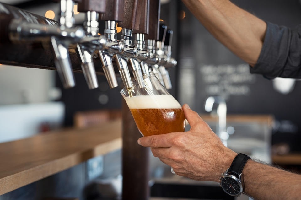 Man pouring draft beer into a glass from a tap