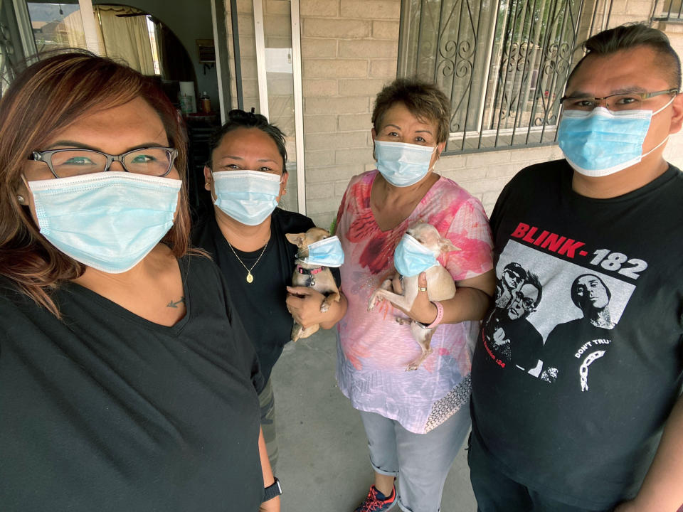 In this June 4, 2020 photo provided by Shannon Todecheene, Todecheene, left, her sister, Erin Gonzales, second from left and her mother, Carol Todecheene, with her brother, Randon Austin, and the family dogs pose in Tucson, Ariz. Carol Todecheene was among those severely hit with the coronavirus. (Shannon Todecheene via AP)