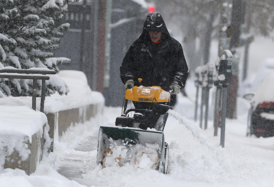 A maintenance man uses a snowblower to clear a sidewalk along 8th Ave. near Lincoln St. as a storm packing snow and high winds sweeps in over the region Tuesday, Nov. 26, 2019, in Denver. Stores, schools and government offices were closed or curtailed their hours while on another front, Thanksgiving Day travellers were forced to wrestle with snow-packed roads and flight delays or cancellations throughout the intermountain West. (AP Photo/David Zalubowski)