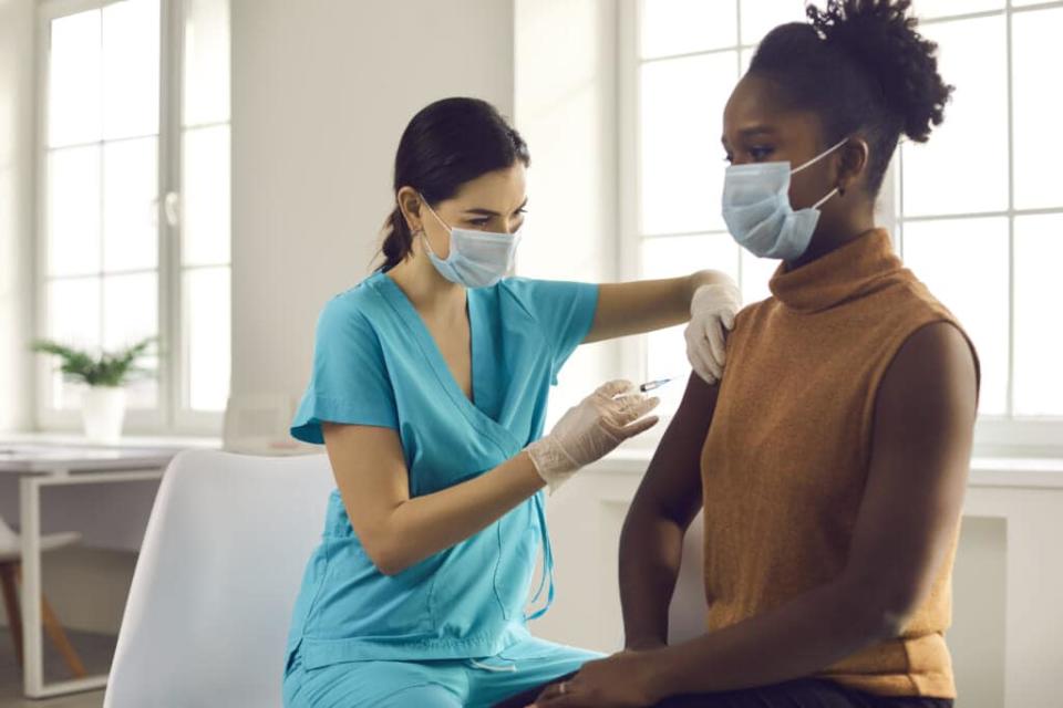 Black woman getting modern flu or Covid-19 vaccine at doctor's office