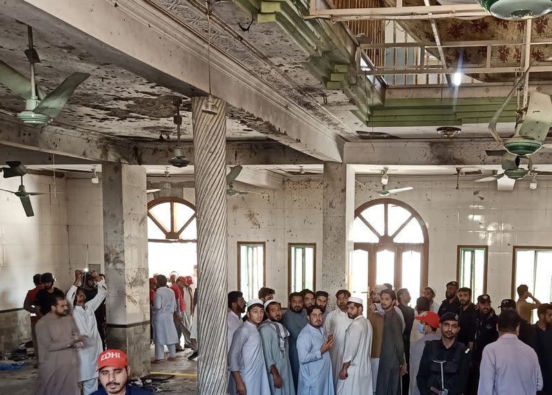 Residents and rescue workers gather at the site of a bomb blast at a religious seminary in Peshawar