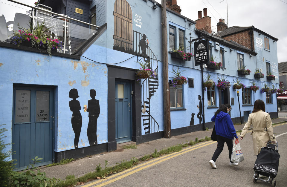 People walks past the Black Horse pub inside the lock down zone, in Leicester, England, Saturday July 4, 2020. England is embarking on perhaps its biggest lockdown easing yet as pubs and restaurants have the right to reopen for the first time in more than three months. One city that is not participating in the easing is Leicester, in central England. The government reimposed lockdown restrictions there, including the closure of schools and nonessential shops, after a spike in new infections. (AP Photo/Rui Vieira)