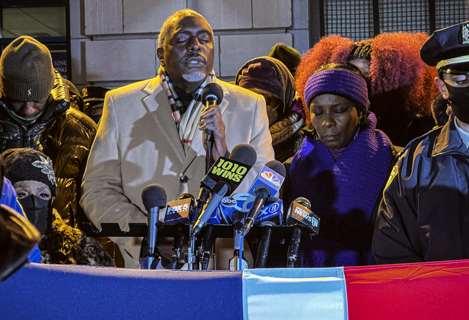 Rev. Ronald Sullivan, center, leads a prayer during a vigil in Harlem outside the 32nd precinct honoring fallen NYPD officers Jason Rivera and Wilbert Mora, Wednesday Jan. 26, 2022, in New York. (AP Photo/Bobby Caina Calvan)