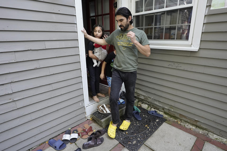 Mohammad Walizada, right, who fled Afghanistan with his family, steps out the back door of their home with two of his daughters, Zahra, left, who holds Kainat Amy, in Epping, N.H., Thursday, Sept. 15, 2022. Since the U.S. military's withdrawal from Kabul last year, the Sponsor Circle Program for Afghans has helped over 600 Afghans restart their lives in their communities. Now the Biden administration is preparing to turn the experiment into a private-sponsorship program for refugees admitted through the U.S. Refugee Admissions Program and is asking organizations to team up with it to launch a pilot program by the end of 2022. (AP Photo/Steven Senne)