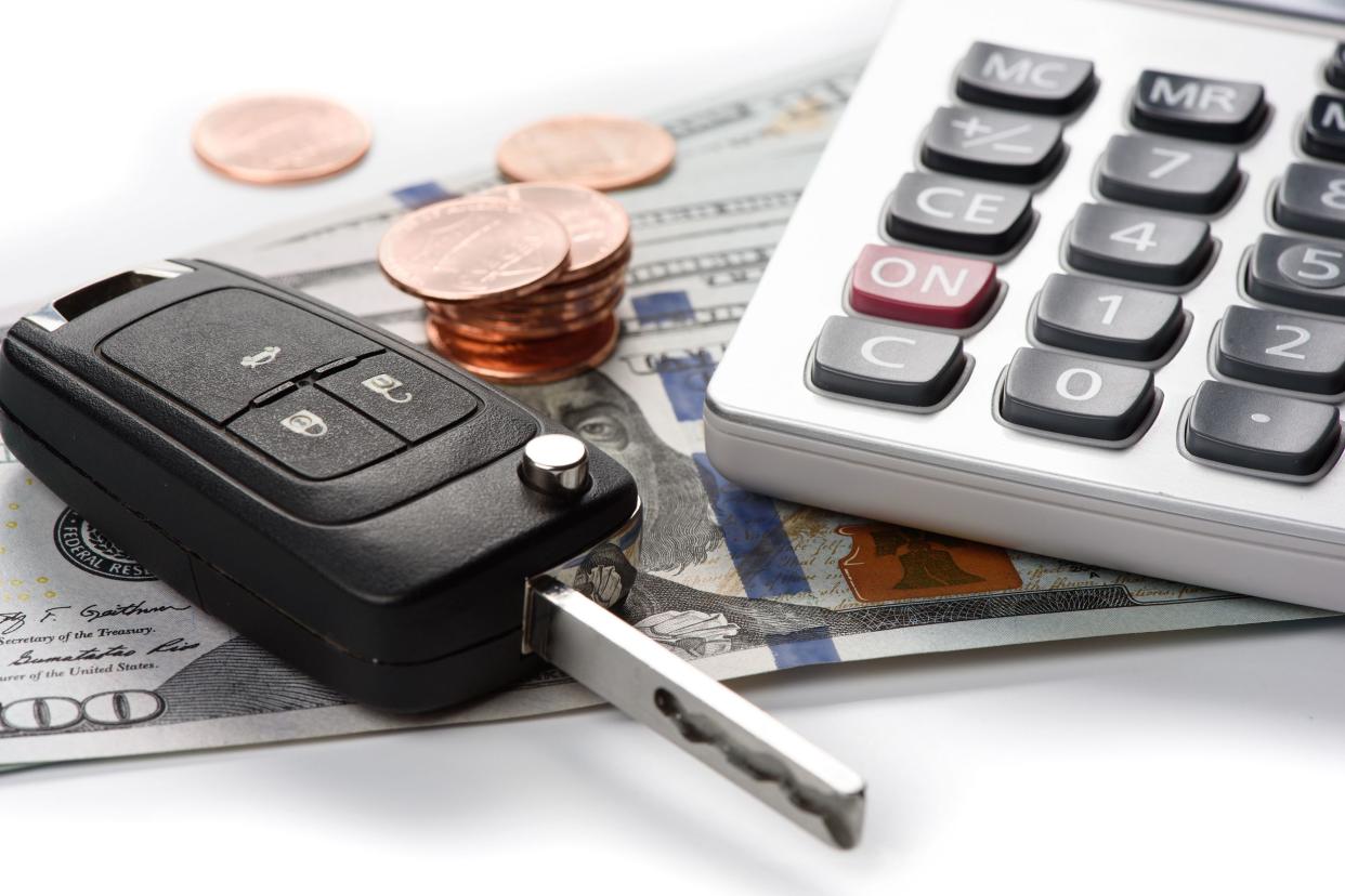 Closeup of car key, calculator, and pennies on numerous us 100 dollar bills